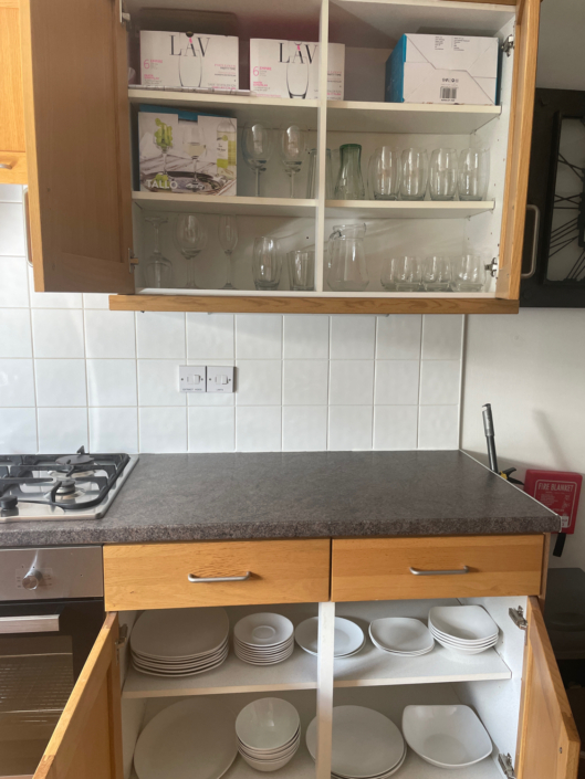 Kitchen cupboards open to show crockery