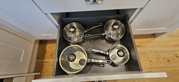 A kitchen cupboard with saucepans