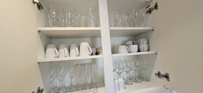 glassware and mugs inside a clean kitchen cupboard